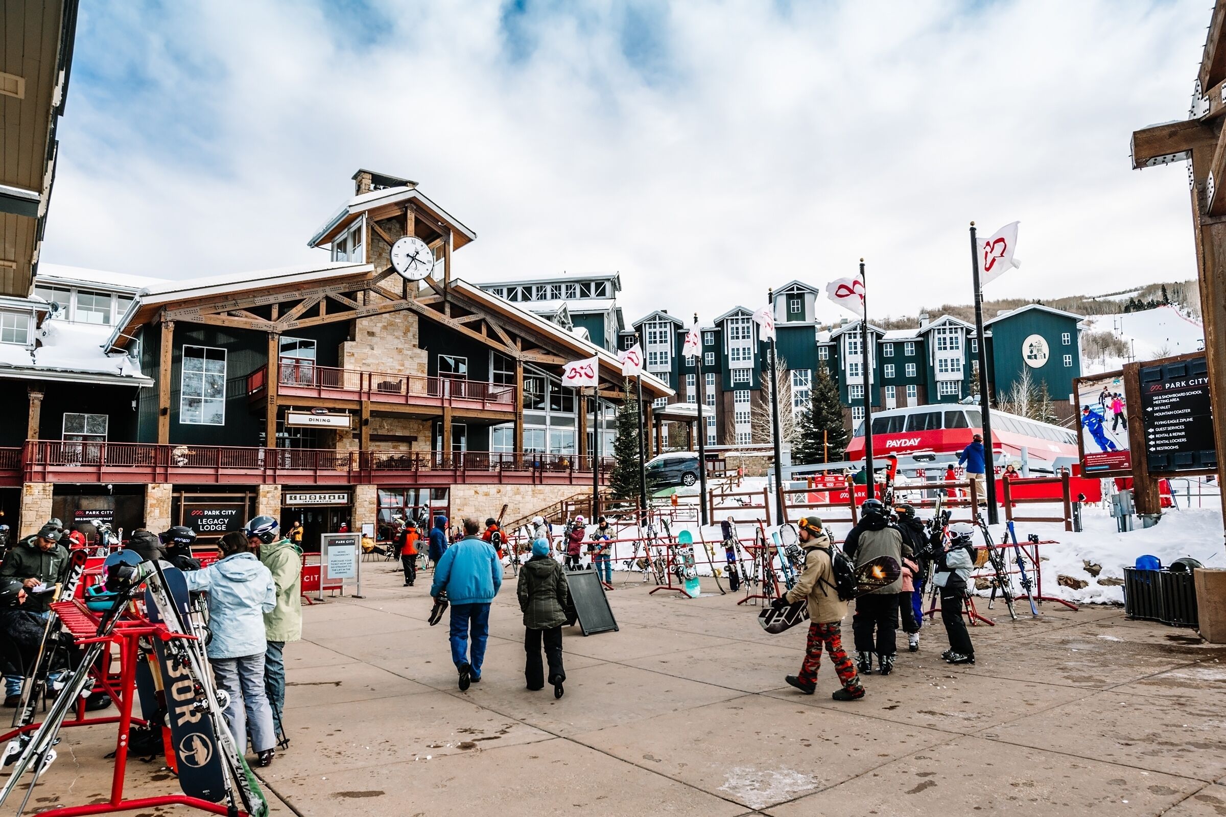 A ski resort with a prominent lodge featuring a clock, ski equipment, and a PayDay bus.