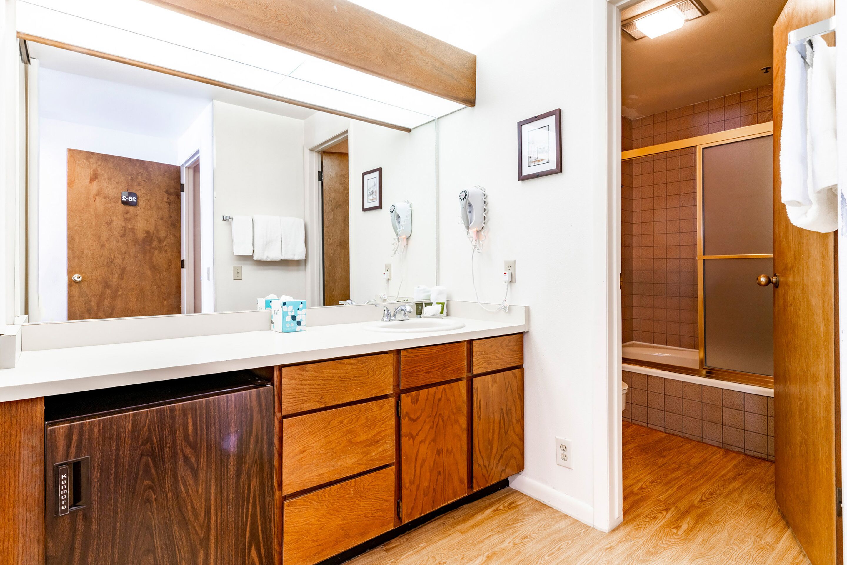 A bathroom with a wooden vanity, a large mirror, and a shower area.