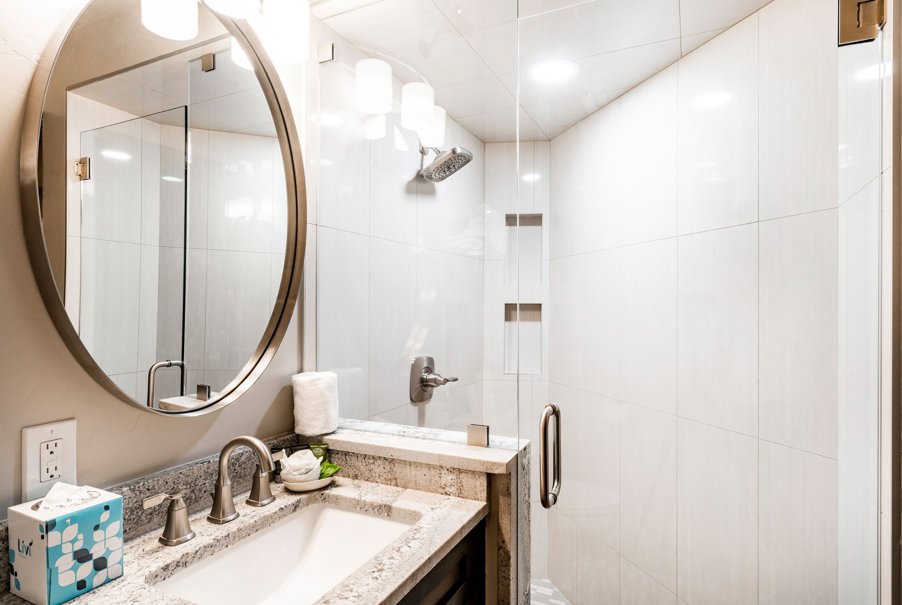 Une salle de bain moderne avec un grand miroir, un lavabo, une douche et des toilettes.