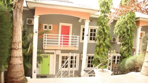 A two-story building with a red door, a balcony, and a staircase leading to the upper floor. - Apo Apartments (Abuja)