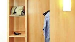Un armario de madera con estantes, barra para colgar ropa y una lámpara.