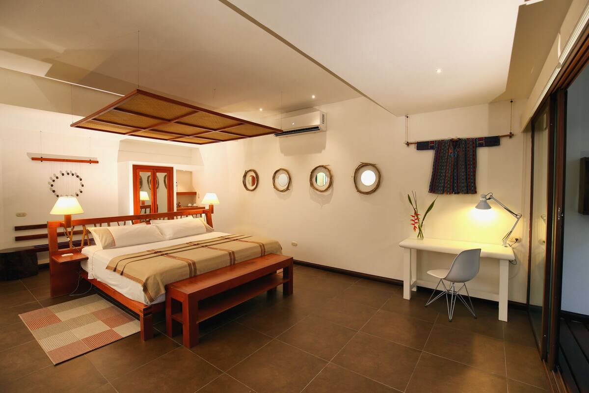 A modern bedroom with a wooden bed, bedside tables, a desk, and a chair.