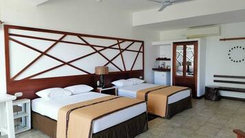 Habitación de hotel con dos camas, un escritorio, una silla, un ventilador de techo y ventana con vistas.