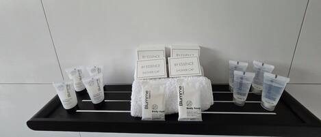 Un estante negro con diversos productos de cuidado corporal Blumme, incluyendo gorros de ducha, jabón corporal y champú.