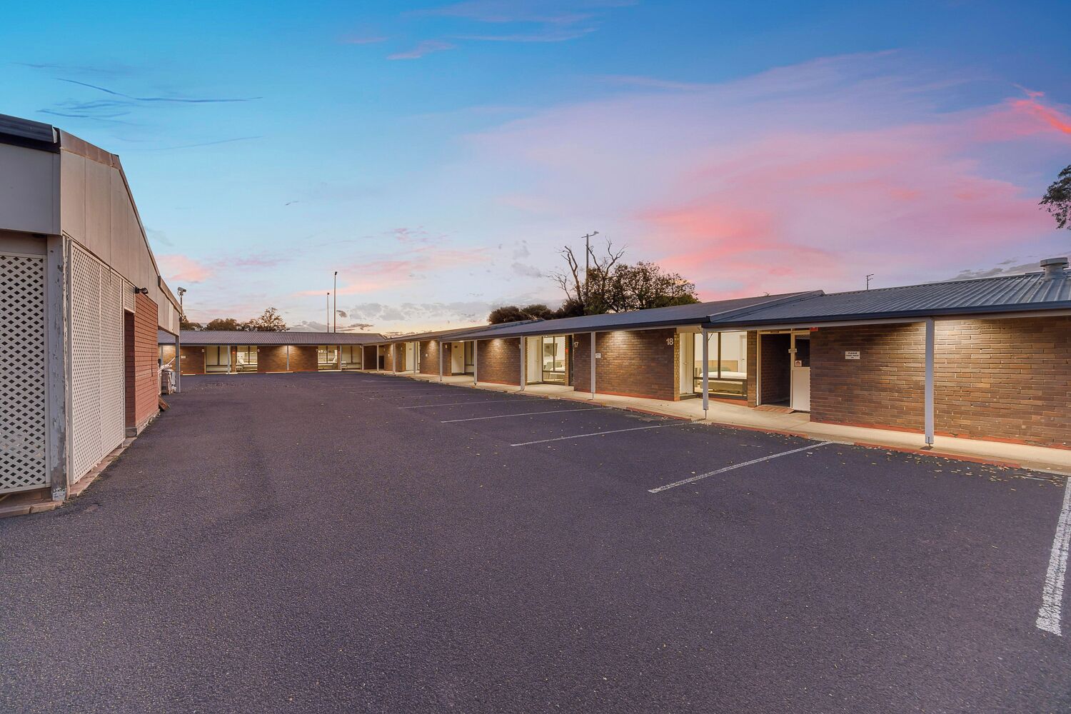 A motel with a parking lot and numbered rooms.