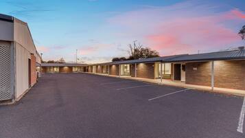 A motel with a parking lot and numbered rooms.