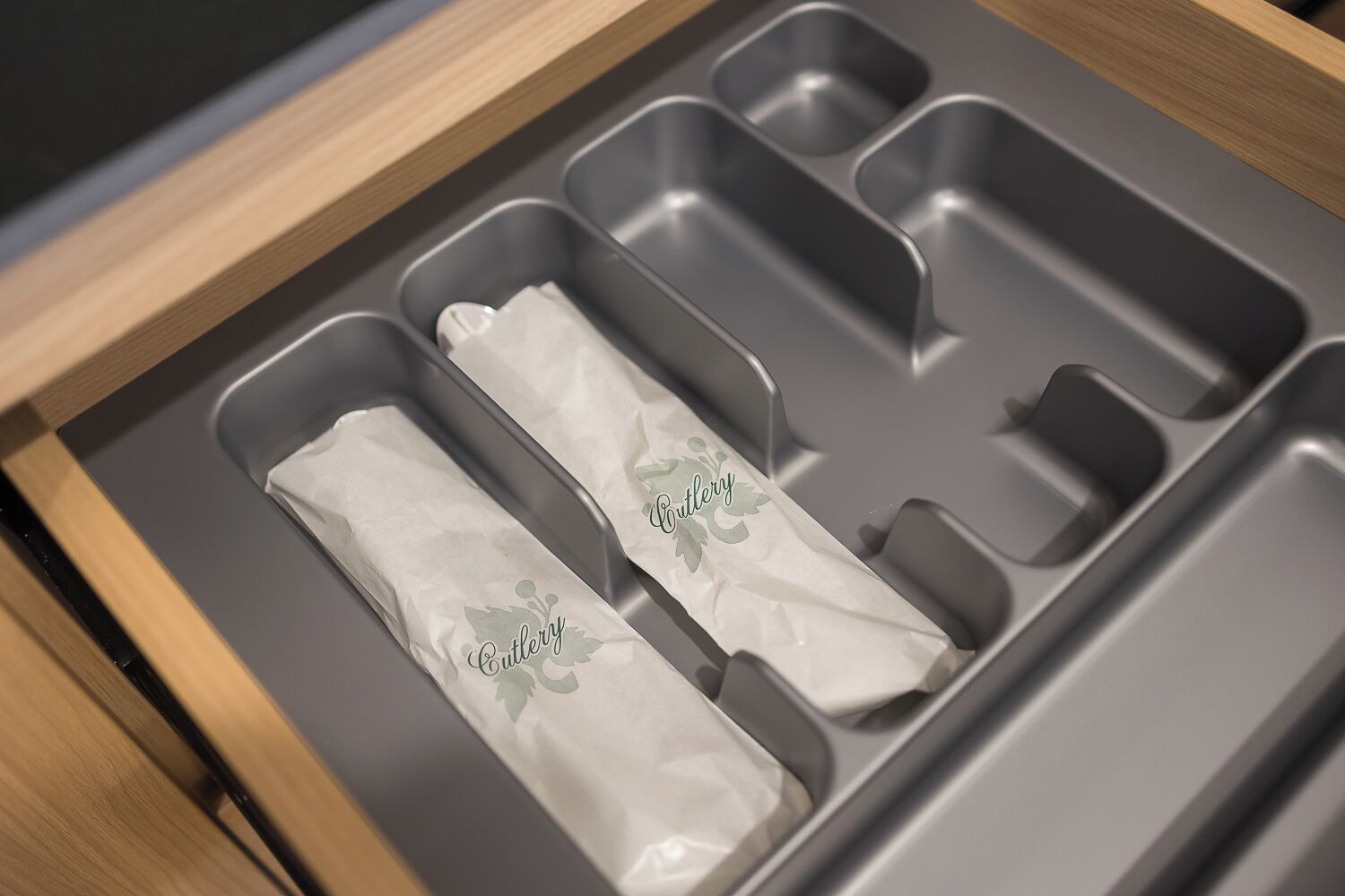 A drawer with three compartments, each containing a tissue with the word "Cutlery" printed on it.