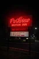 Señal de neón del Parkview Motor Inn que indica 'NO DISPONIBLE' y ofrece comodidades como Wi-Fi, piscina y una amplia sala familiar.