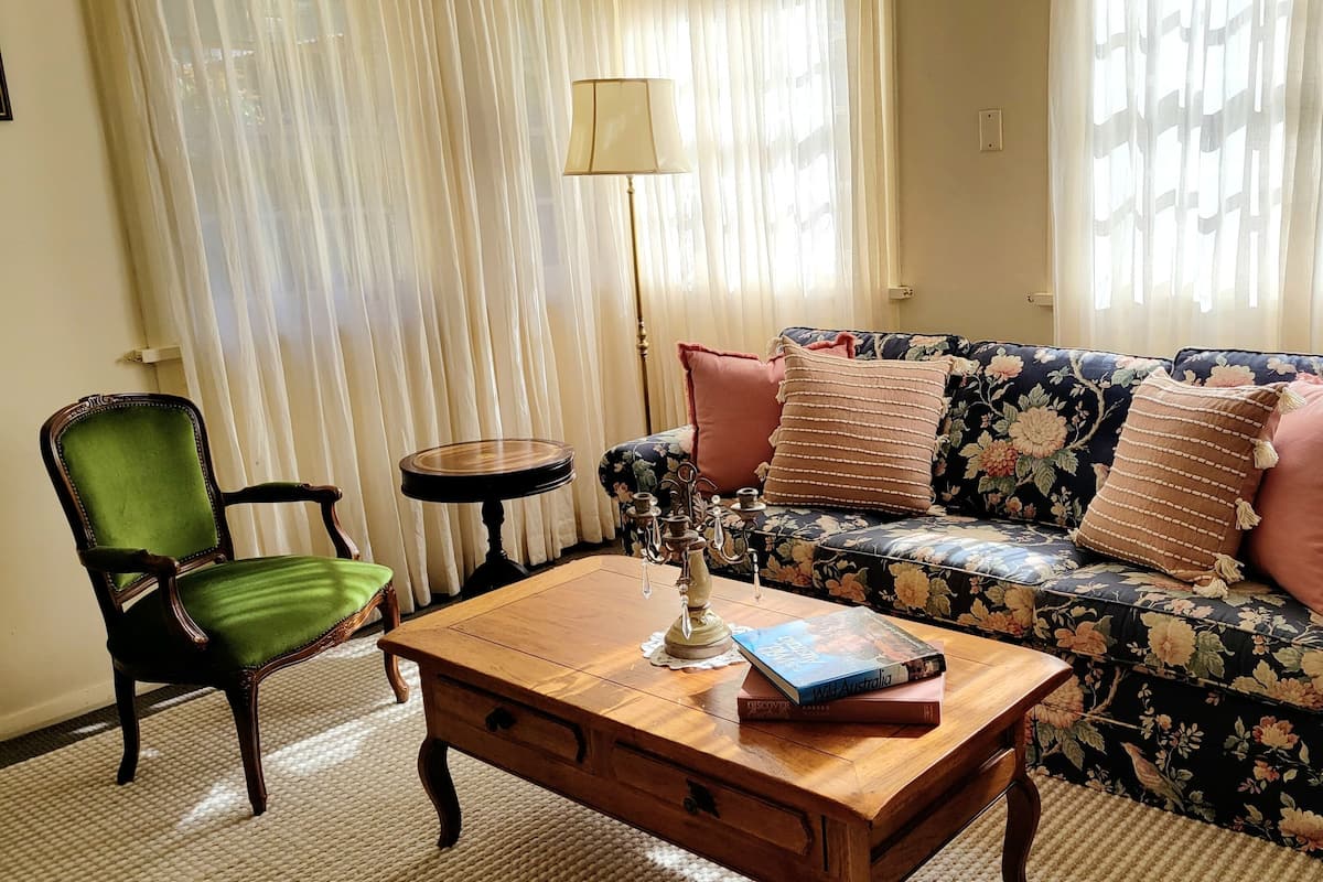A living room with a floral sofa, a green chair, a wooden coffee table, and a floor lamp.