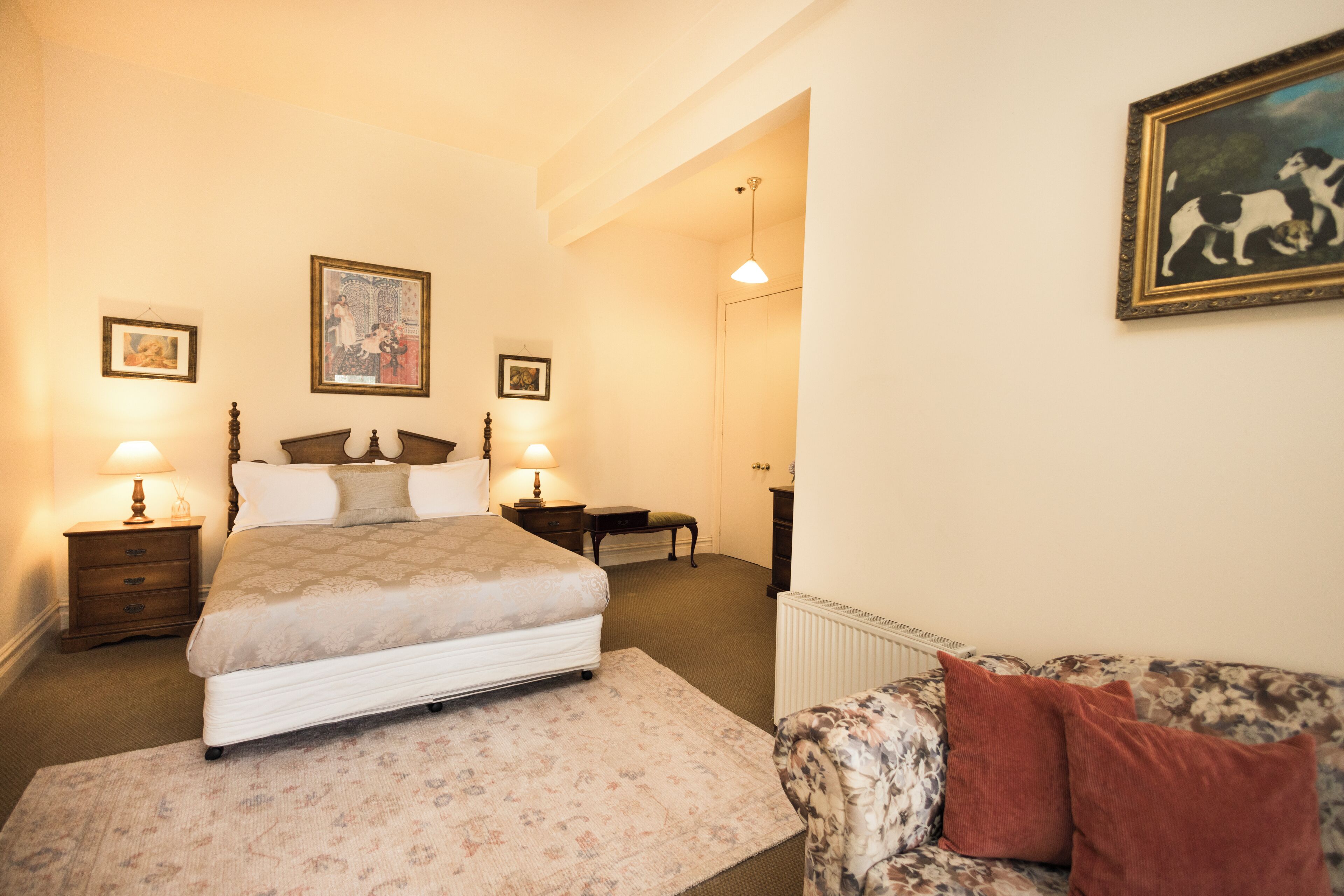 Une chambre à coucher avec un lit, des tables de chevet, une commode, une chaise et un tableau au mur.
