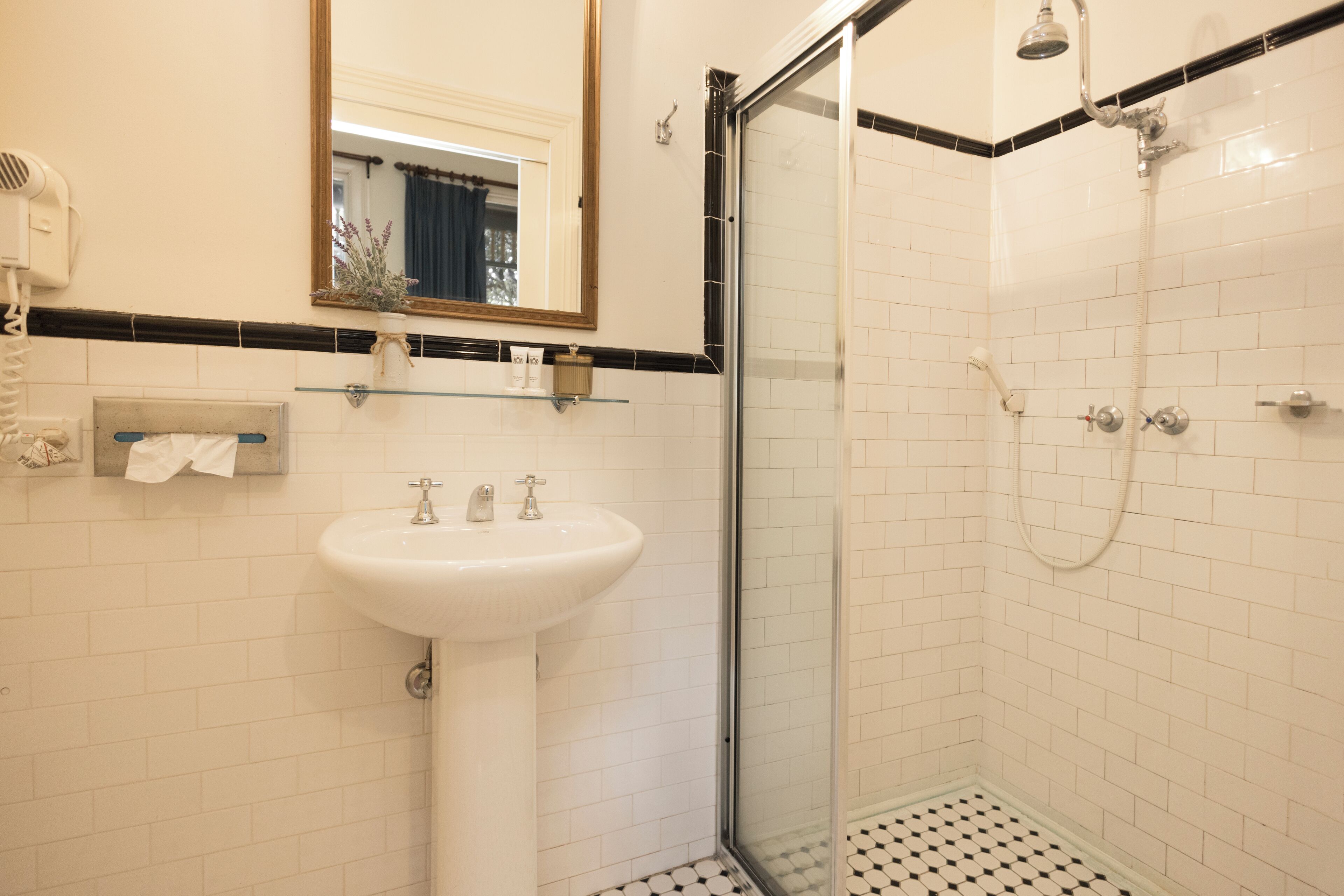 Une salle de bain avec un lavabo blanc, une cabine de douche en verre et un miroir au-dessus du lavabo.