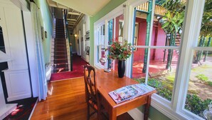 A dining area with a wooden table, chairs, and a vase of flowers. A staircase is visible in the background. - Leura House (Leura)