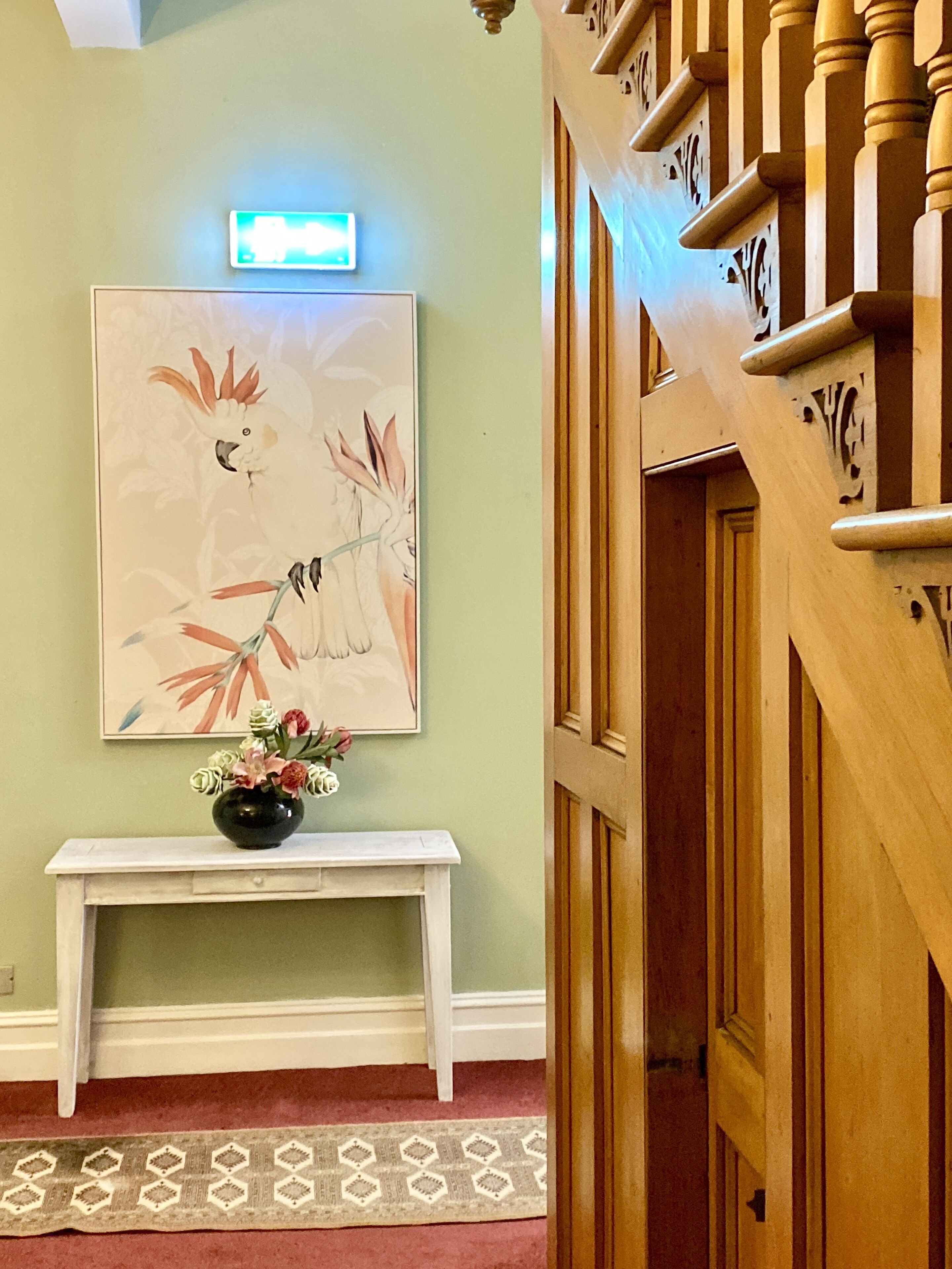 A staircase with a wooden handrail and a wall-mounted light.