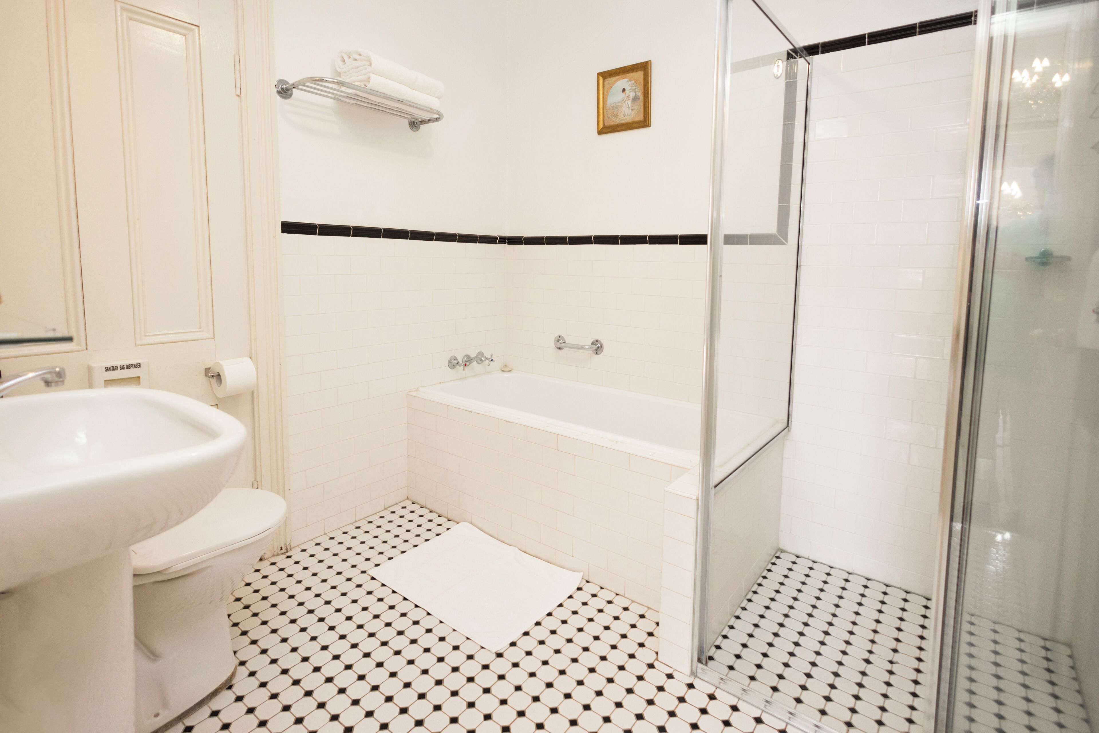 Un baño con lavamanos, inodoro, bañera y zona de ducha con mampara de vidrio.