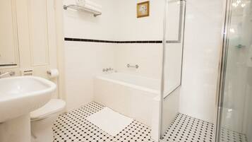 A bathroom with a sink, toilet, bathtub, and a glass-enclosed shower area.