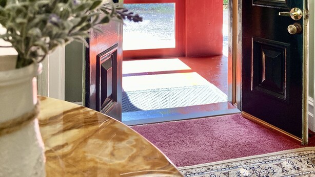 A doorway leading to a red-walled room with a view of greenery outside. - Leura House (Leura)