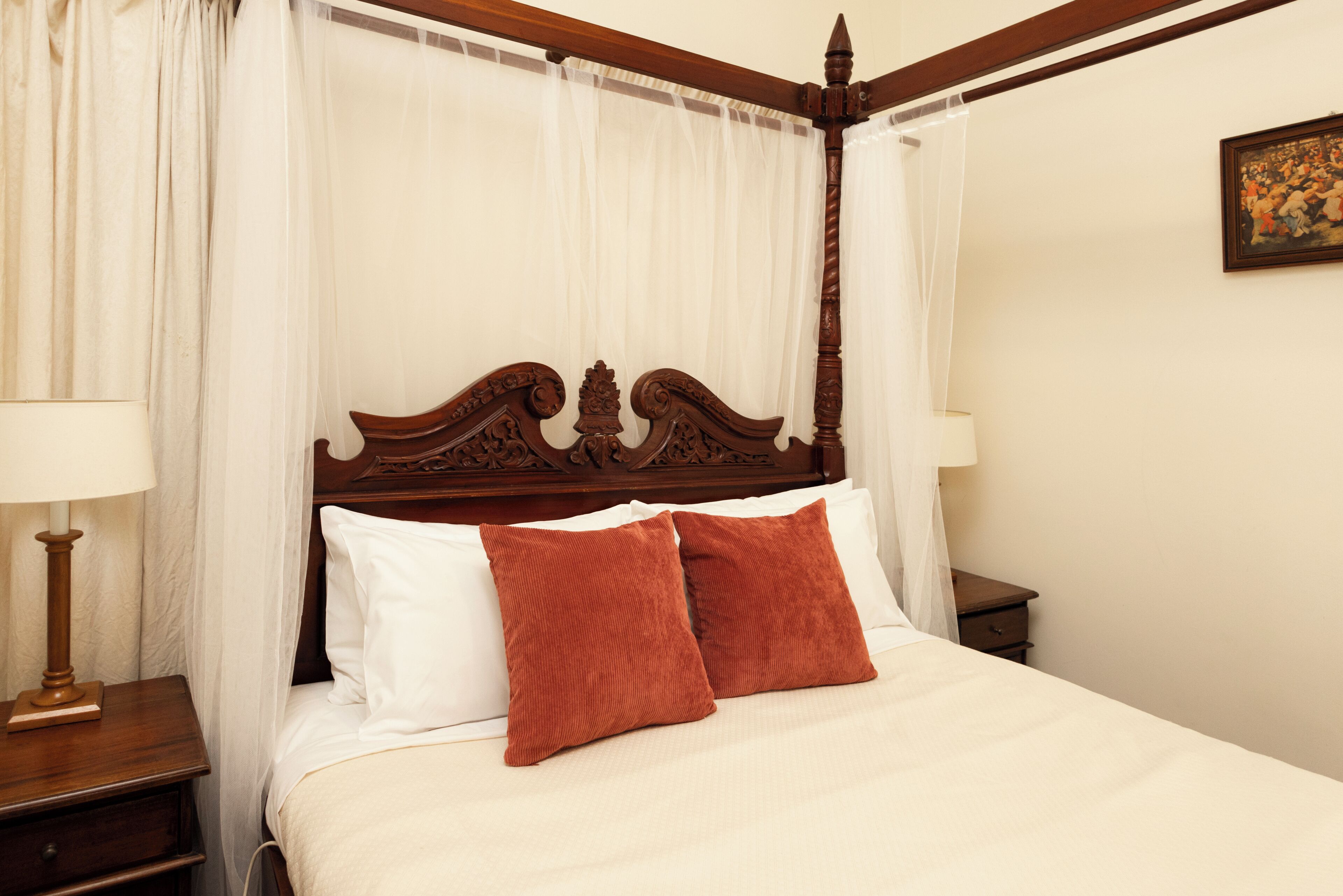 A four-poster canopy bed with white linens and two brown pillows.
