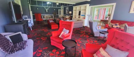 A living room with red and grey furniture, a patterned carpet, and a television.