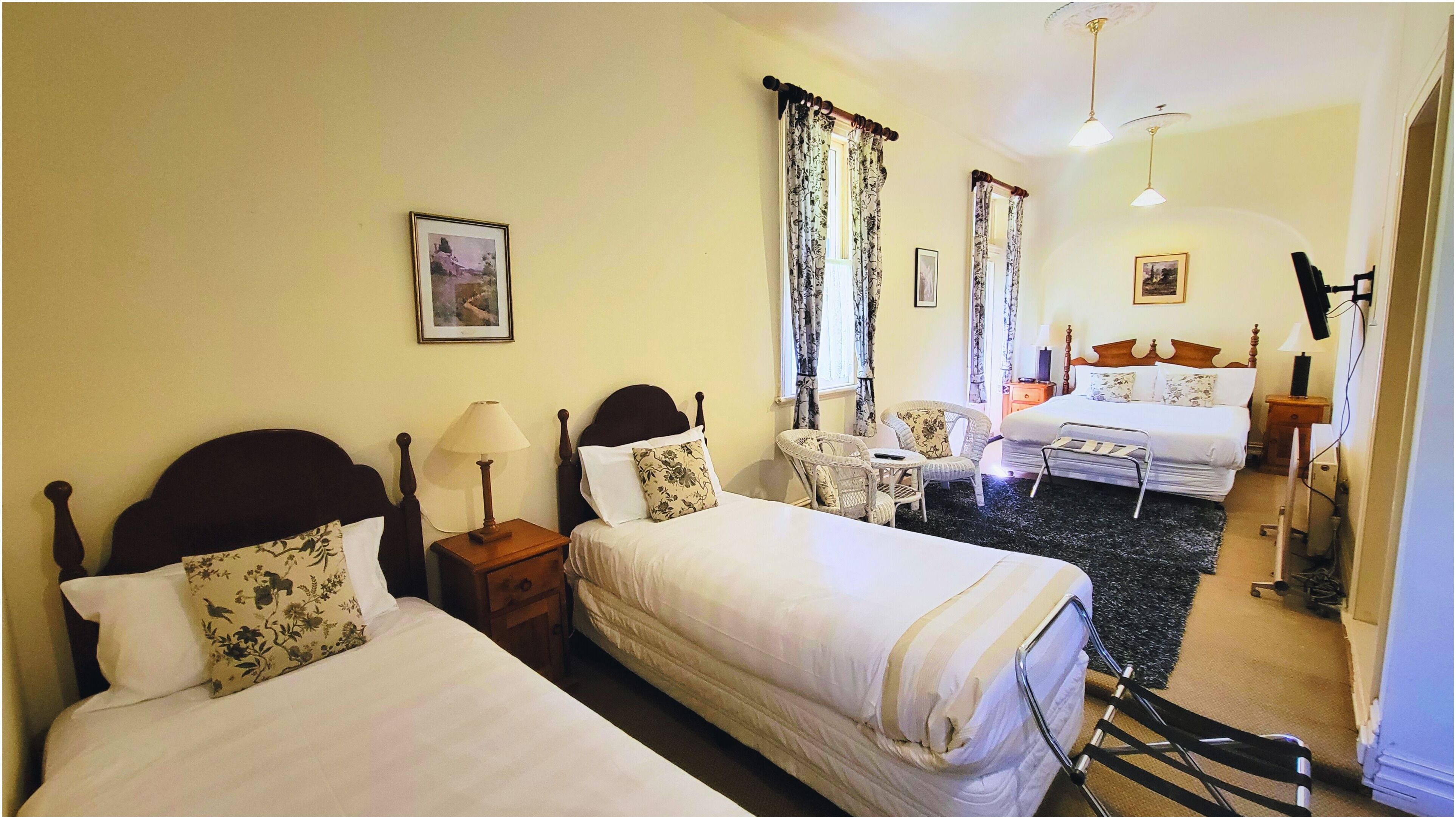 A hotel room with two beds, a chair, a desk, and a small table.