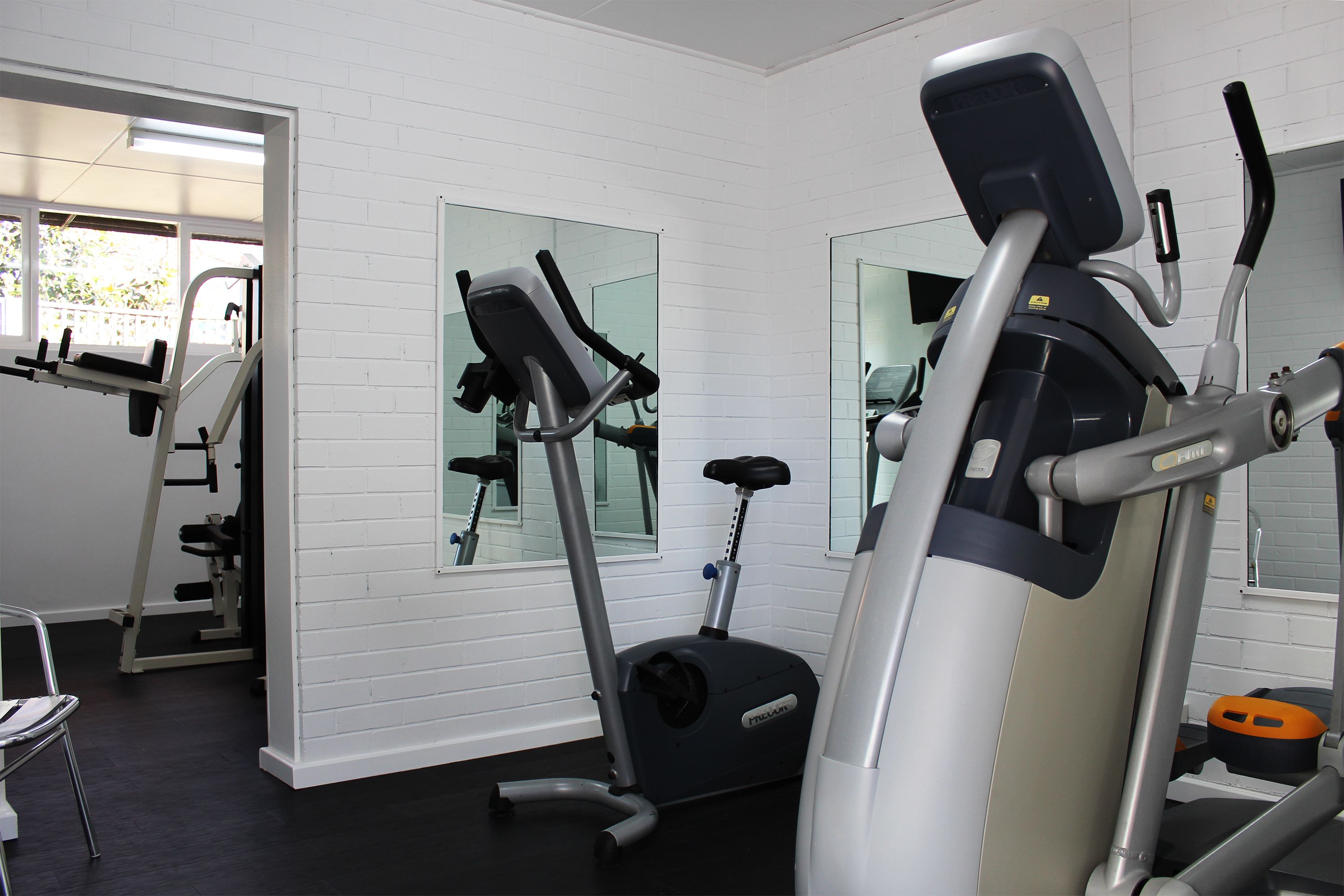 A gym with exercise equipment, a mirror, and a window.