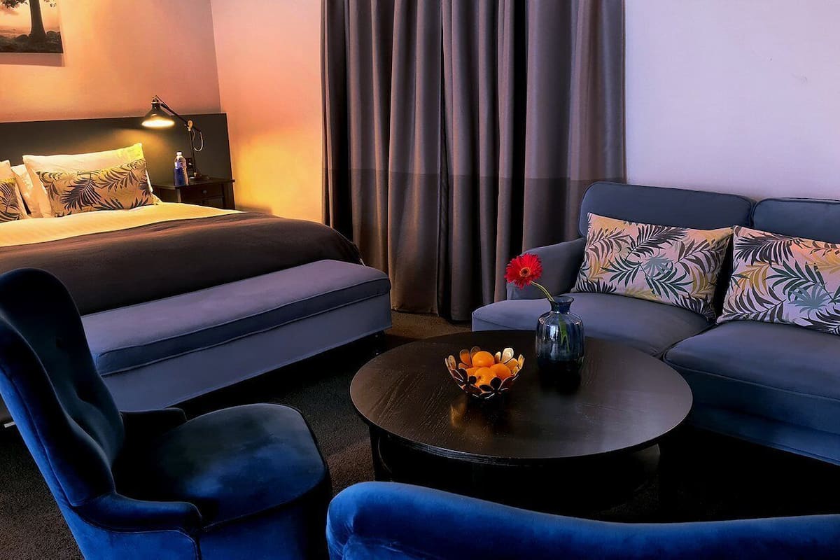 A hotel room with a bed, a sofa, a chair, and a coffee table.