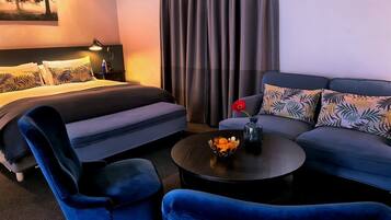 A hotel room with a bed, a sofa, a chair, and a coffee table.