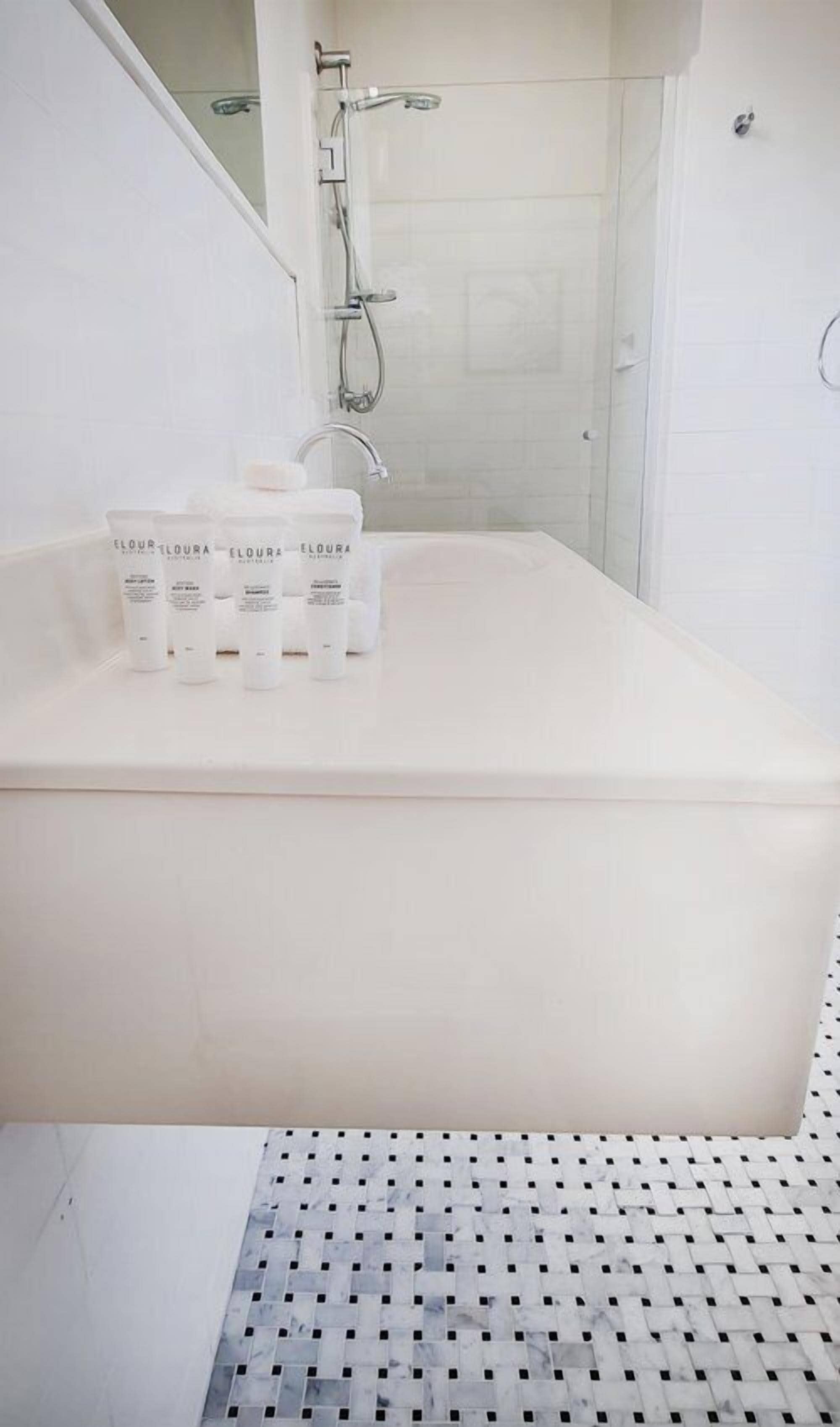 A modern bathroom with a white bathtub, a shower, and a tiled floor.