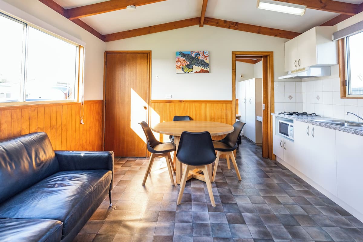 Una cocina acogedora con comedor, vigas de madera en el techo y un ventanal grande.