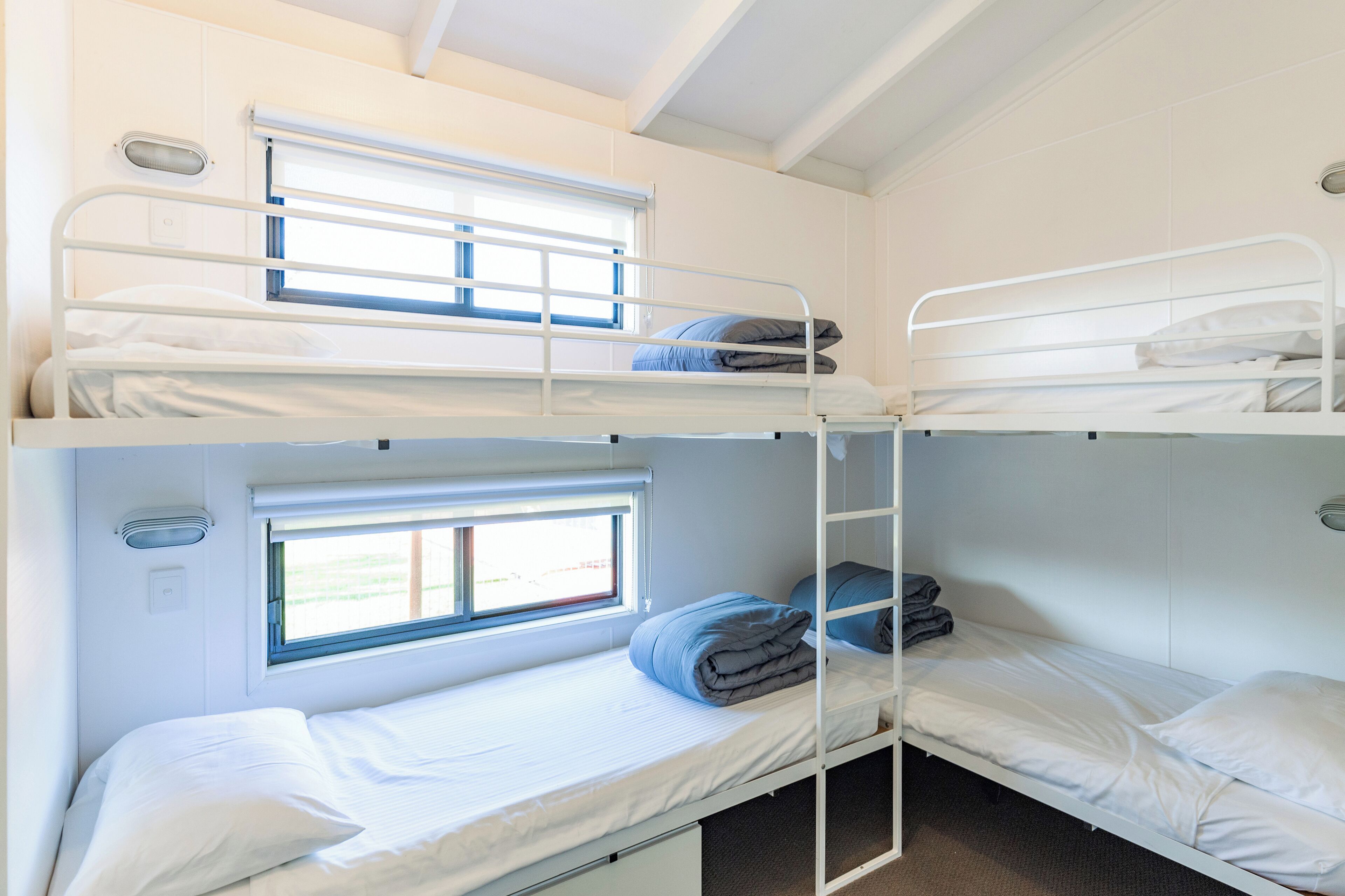 Dormitorio con literas, tres camas y una ventana en cada una.