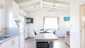 Una cocina moderna con armarios blancos, un microondas y una zona de comedor con mesa y sillas.