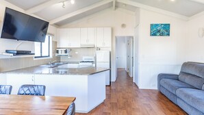 Una cocina moderna con armarios blancos, una isla central y un televisor de pantalla plana.
