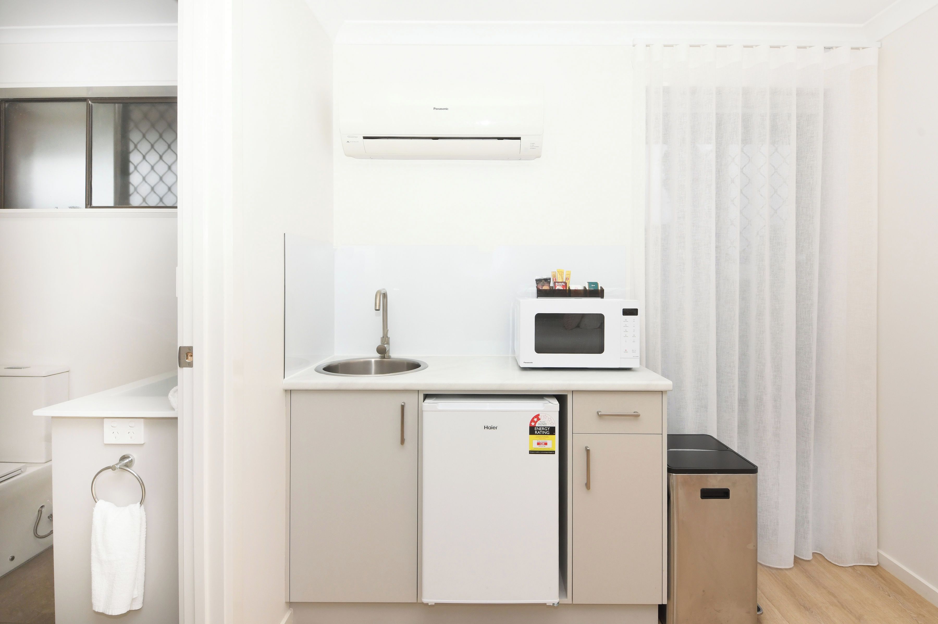 Une petite cuisine équipée comprenant un réfrigérateur, un four à micro-ondes, un évier et une petite poubelle.