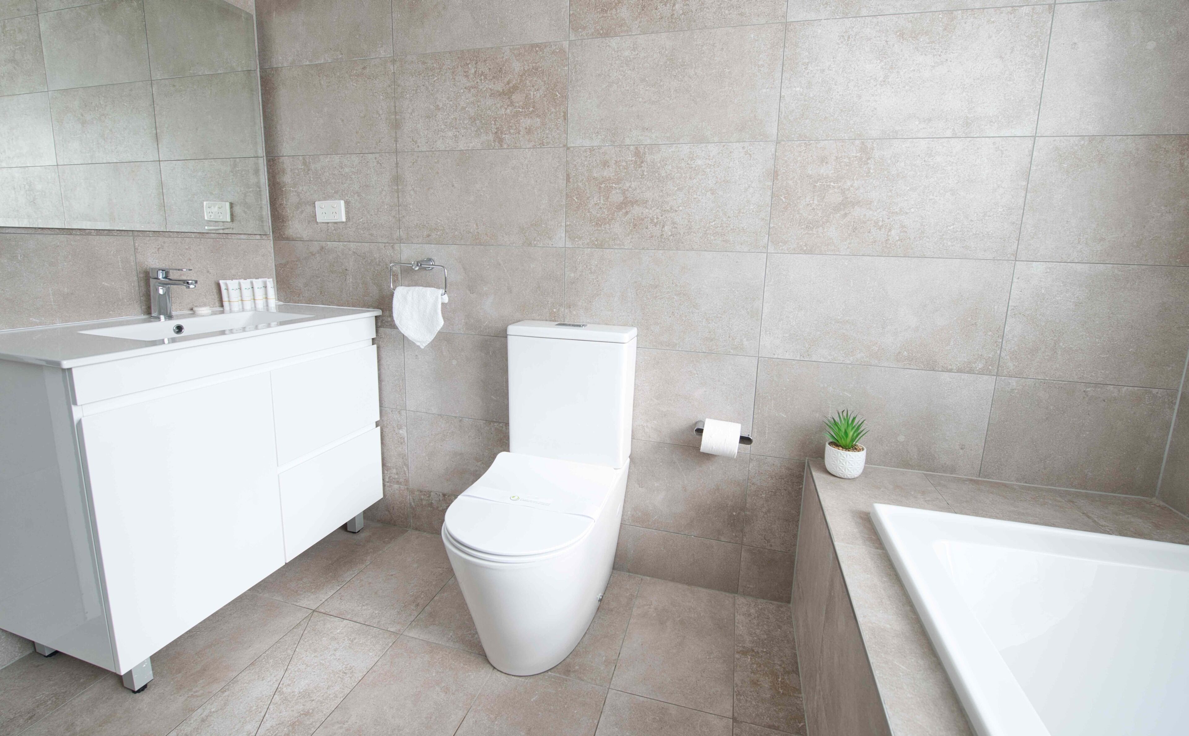 Un baño moderno con lavamanos, inodoro y bañera blancos.