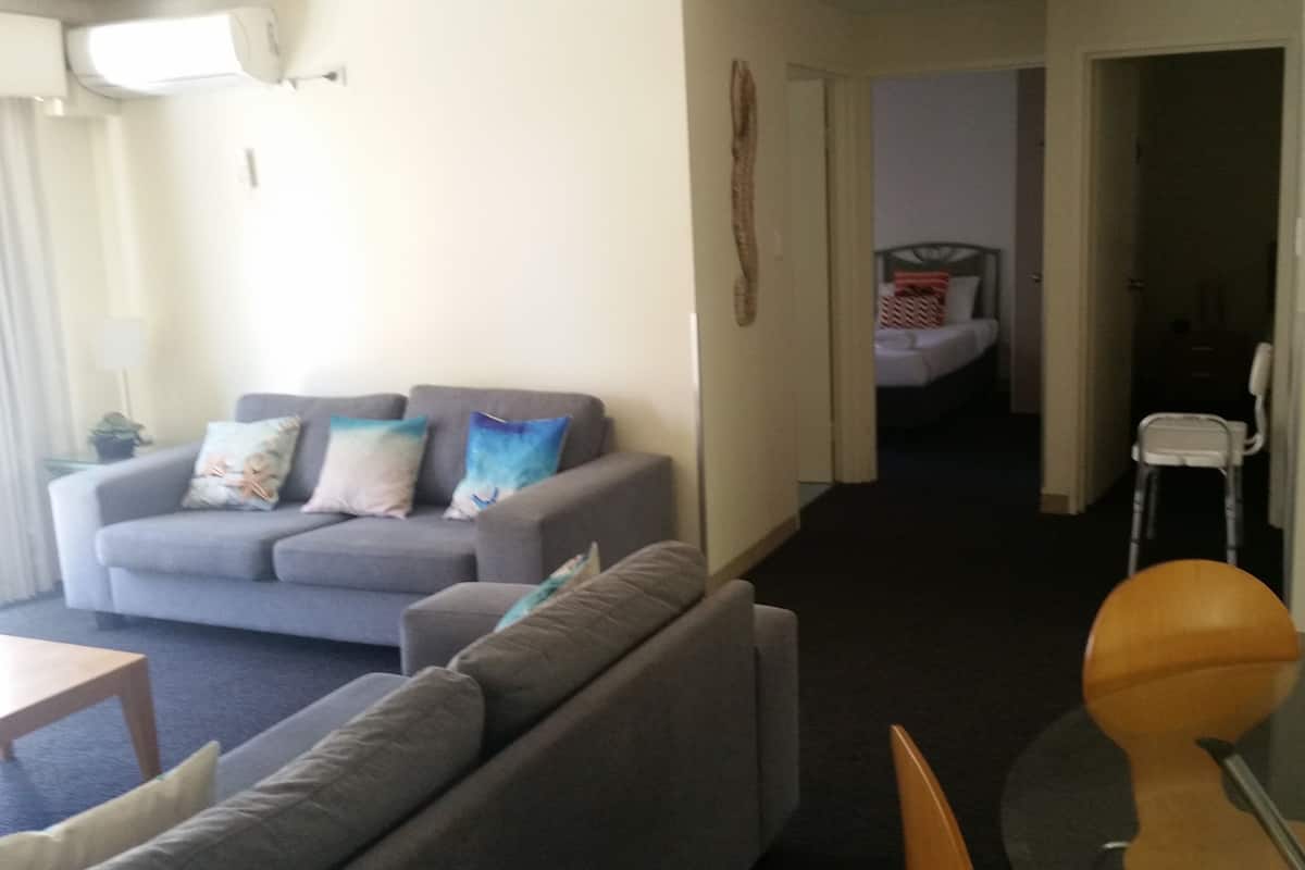 Ein Wohnzimmer mit grauem Sofa, einem Holztisch und einem Essbereich mit Stuhl und Tisch.