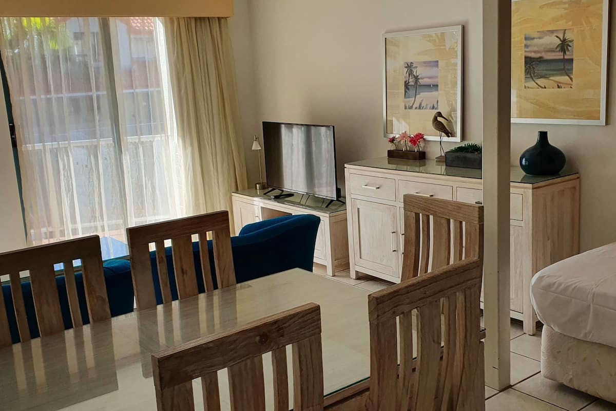 Ein Zimmer mit Esstisch, Stühlen, einer Couch, einem Fernseher, einem Schrank und einem Bett.