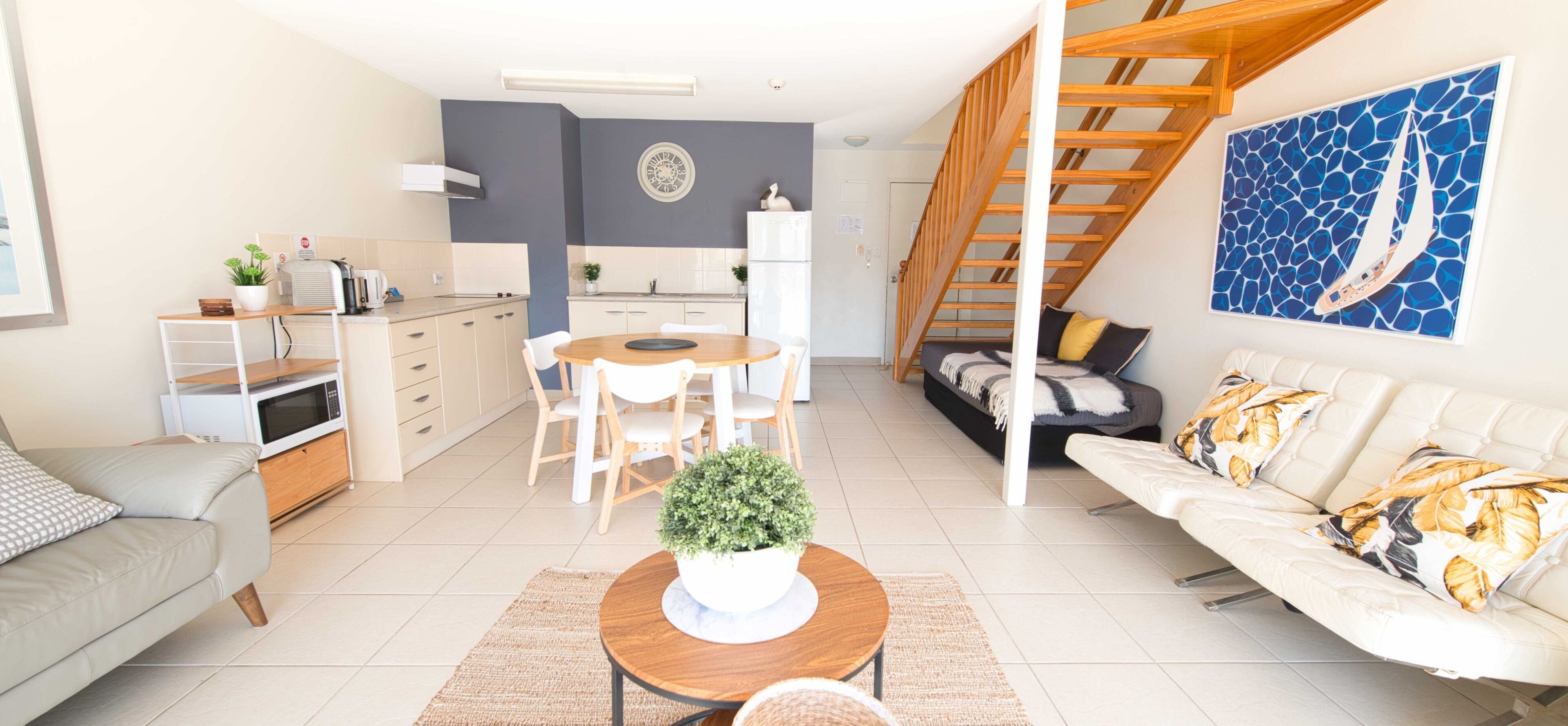A modern apartment with a dining area, kitchen, living room, and a staircase.