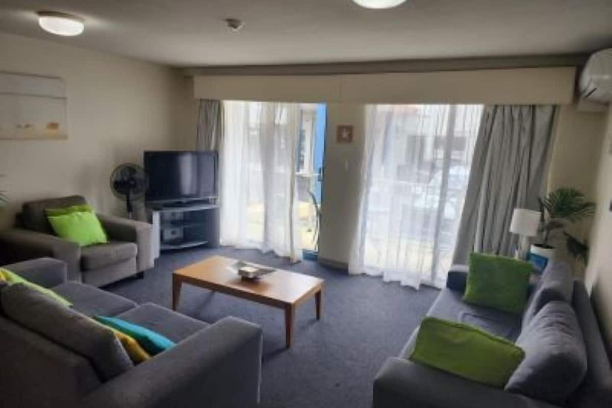 Ein Hotelzimmer mit einer Sofagarnitur, einem Fernseher, einem Couchtisch und einem fensterbepflegten Fenster.