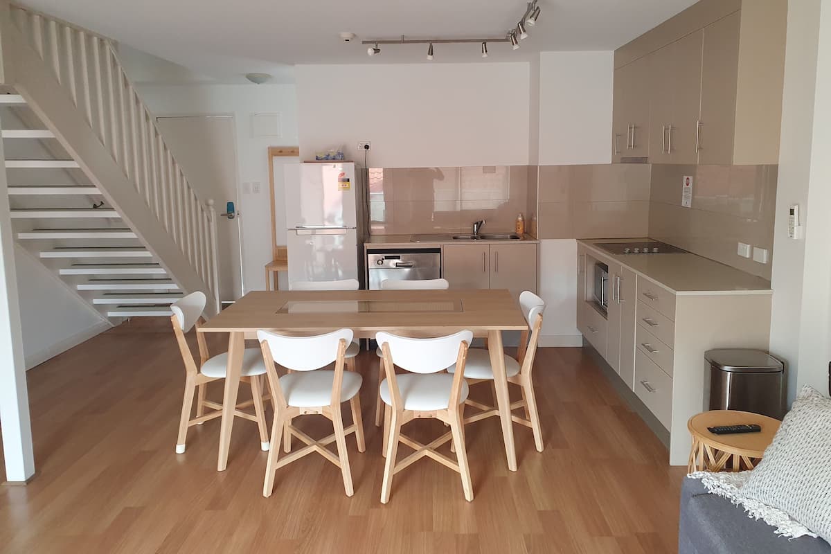 Eine moderne Küche mit Essbereich, Holzboden und einer Treppe.