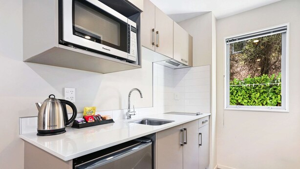 A modern kitchen with a built-in microwave, stainless steel kettle, and a dishwasher. - Quality Suites Amore (Christchurch)