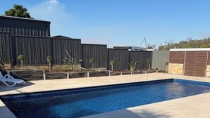 A swimming pool with a tiled deck, a fenced area, and a building in the background. - Barooga River Gums Motor Inn (Barooga)