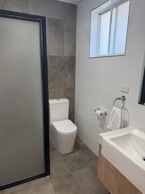 A bathroom with a toilet, a sink, and a window. - Barooga River Gums Motor Inn (Barooga)