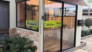 A reception area with a sign indicating 24-hour service, a reception desk, and a door leading inside. - Barooga River Gums Motor Inn (Barooga)