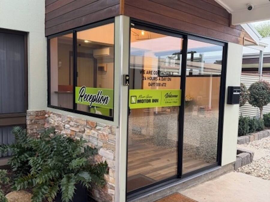 A reception area with a sign indicating 24-hour service, a reception desk, and a door leading inside.