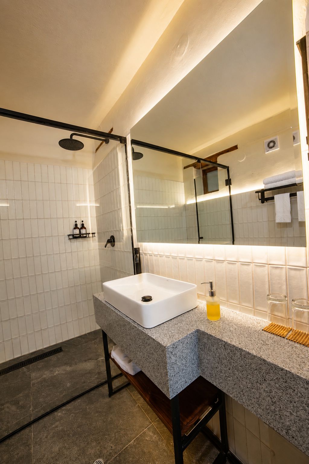 A modern bathroom with a large mirror, a white sink, and a shower area.