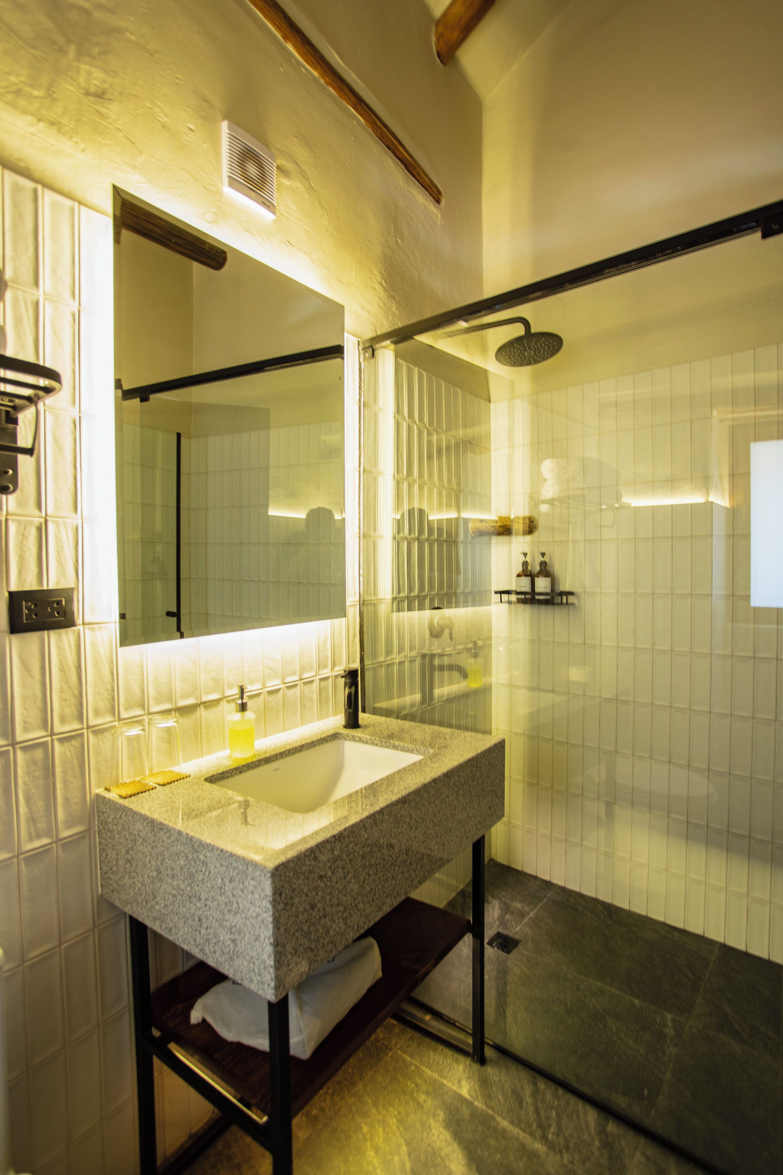 Un baño moderno con un espejo grande, un lavabo y una zona de ducha.