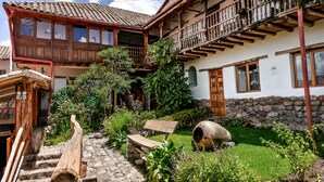 Una casa in legno tradizionale con una scala in pietra, una panchina di legno e un giardino con un pozzo in pietra.