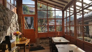 Una stanza rustica con pareti in pietra, arredi in legno e ampie finestre che si affacciano sul paesaggio circostante.