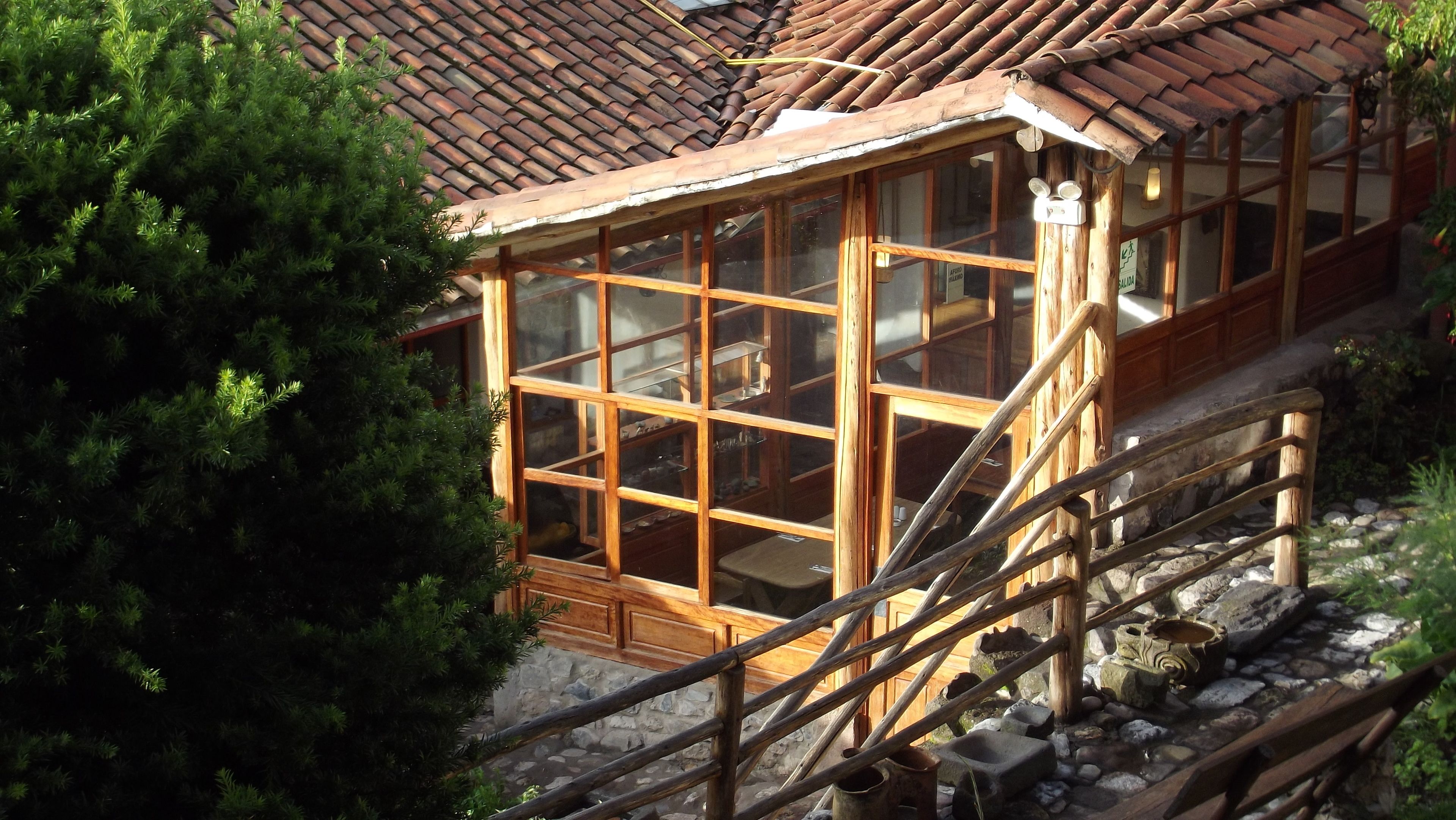 A wooden cabin with a glass enclosure, stone steps, and a wooden railing.