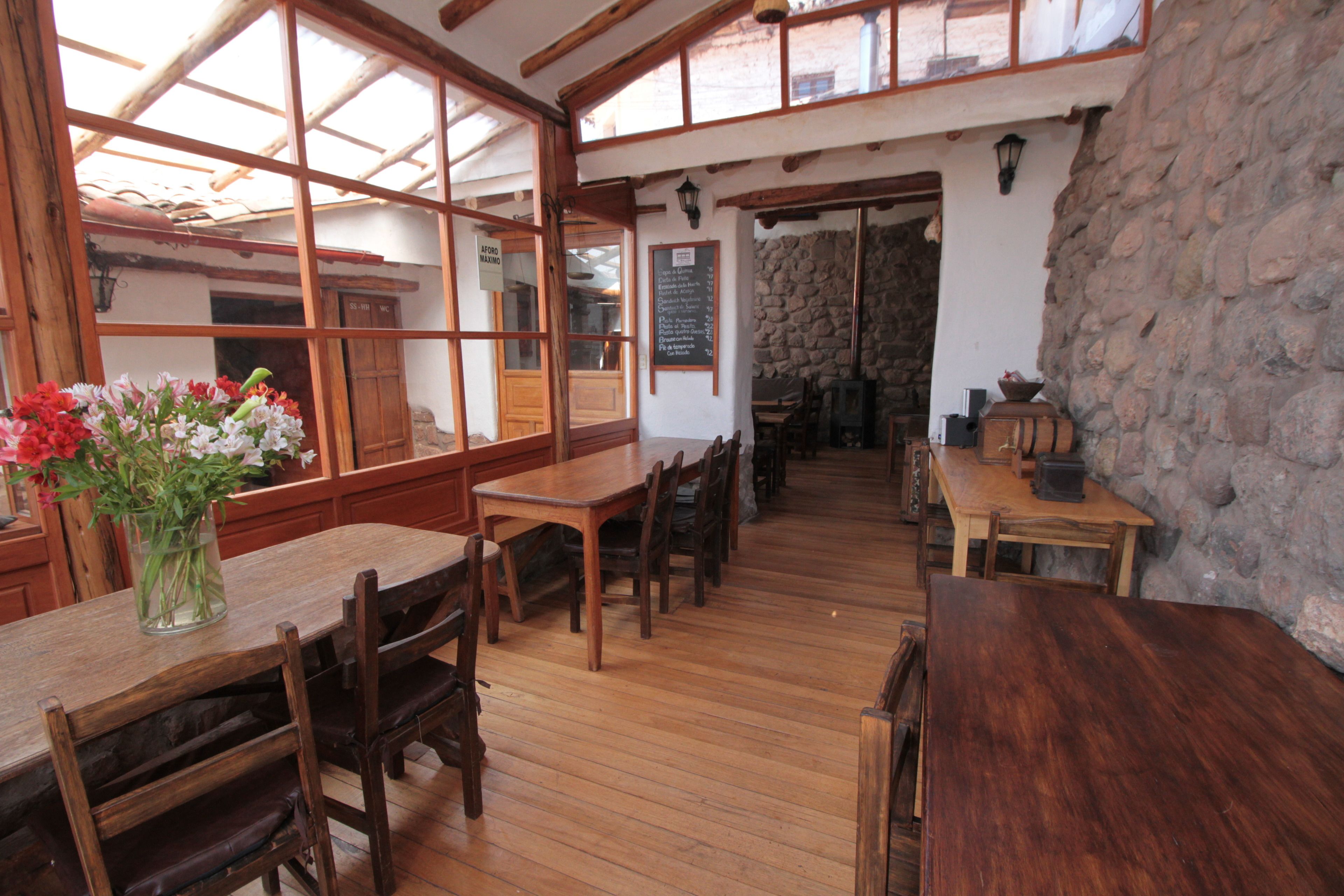 A rustic interior with wooden tables and chairs, stone walls, and a large window.