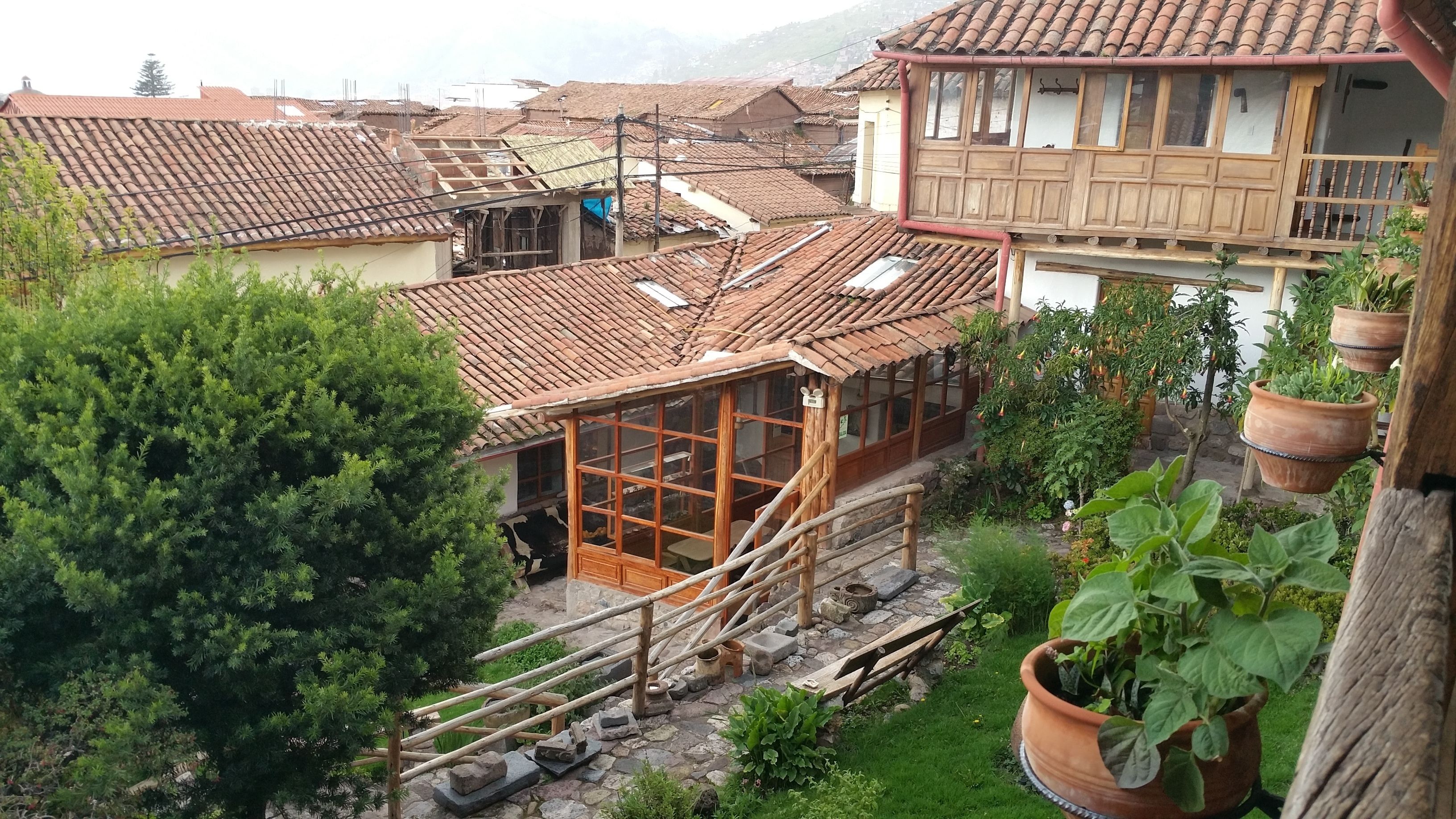A traditional house with a tiled roof, wooden balcony, and potted plants.